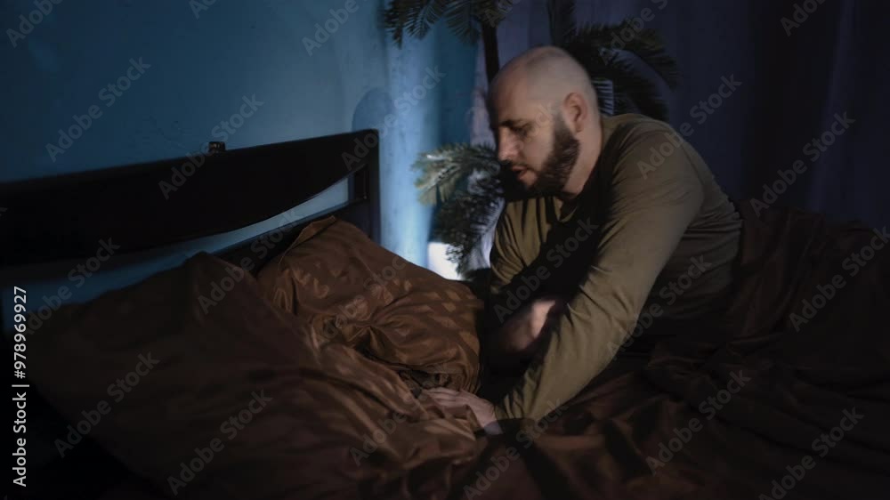 Concept of rest and healthy sleep. Young bearded man lies down to sleep adjusting pillow on bed for comfortable sleep Concept of rest and healthy sleep. Young bearded man lies down to sleep adjusting pillow on bed for comfortable sleep