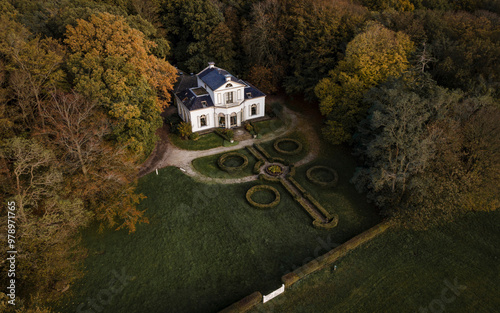 Aerial view of a beautiful house surrounded by a serene forest in autumn sunset, Oudemirdum, Netherlands.