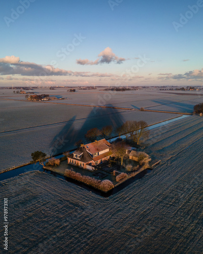 Aerial view of a tranquil winter landscape with a farm and frosted meadow at sunrise, Sneek, Netherlands. photo