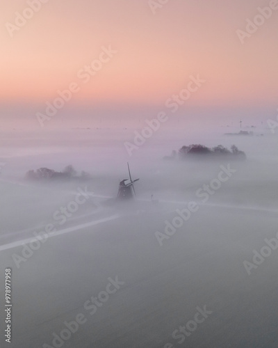 Aerial view of tranquil windmill in fog at sunrise, Cornwerd, Netherlands. photo