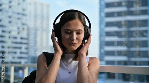 Happy beautiful young woman in headphones listening to music, outdoors