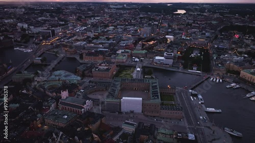 Aerial views showcase Stockholm city center illuminating during blue hour, highlighting the Royal Palace and canals with boats photo