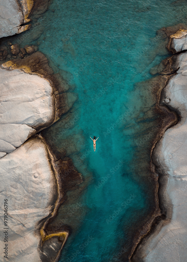 Aerial view of beautiful rocky coastline with crystal clear water and a swimmer, Triovassalos, Greece. Aerial view of beautiful rocky coastline with crystal clear water and a swimmer, Triovassalos, Greece.