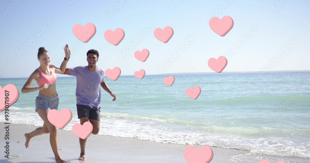 Obraz premium Image of pink hearts over diverse couple running on beach