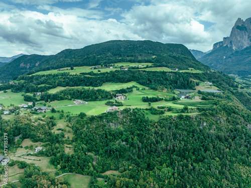 Aerial view of serene village surrounded by green hills and mountains in the Dolomites, Kastelruth, Italy. photo