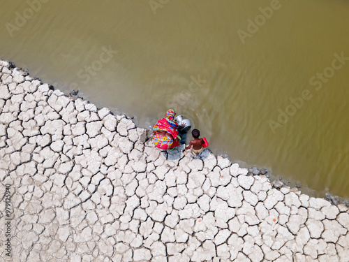 Aerial view of a coastal village facing drought with cracked earth and a community collecting water, Khulna, Bangladesh. photo