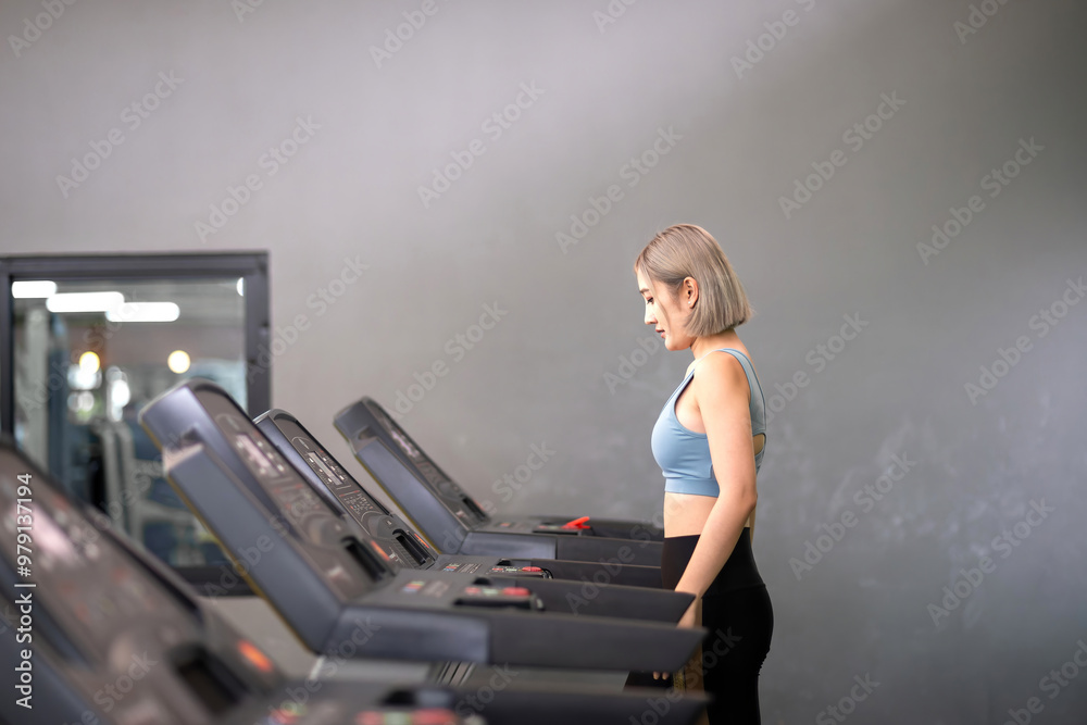 Fototapeta premium fitness asian exercise woman running device treadmill. healthy fitness trainer jogging on treadmill to exercise legs muscle. adult woman running treadmill burn fat and calories on electric equipment