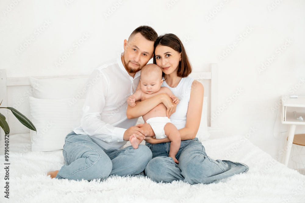 mom, dad with a baby, an international family, a Caucasian mom with an Asian husband and a baby in her arms in the bedroom gently hugs the baby holding in her arms, a place for text