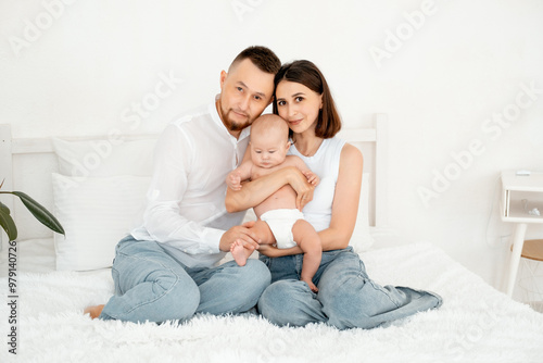 mom, dad with a baby, an international family, a Caucasian mom with an Asian husband and a baby in her arms in the bedroom gently hugs the baby holding in her arms, a place for text