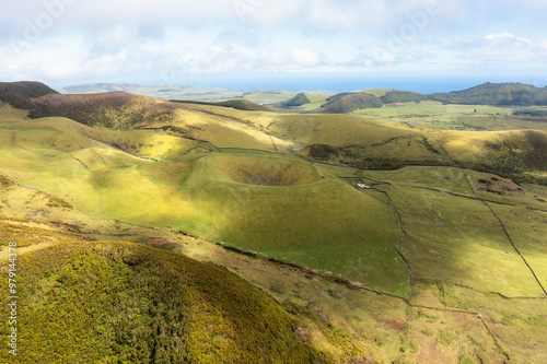 Aerial view of the volcanic crater of Algar do Carvao surrounded by serene hills and expansive fields, Porto Judeu, Portugal. photo