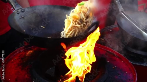 Street-side wok fire in slow motion. Slowmo cook fires up hot oil with vegetables outside on the road at night in downtown. chef cooking delicious fried noodles