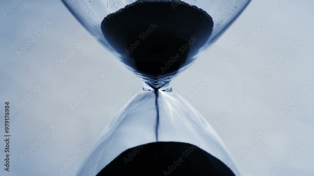 A close shot of countdown beads falling through an hourglass in slow motion