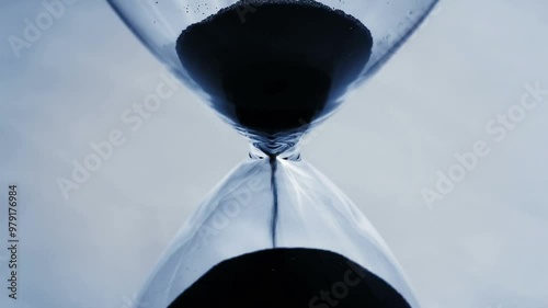 A close shot of countdown beads falling through an hourglass in slow motion