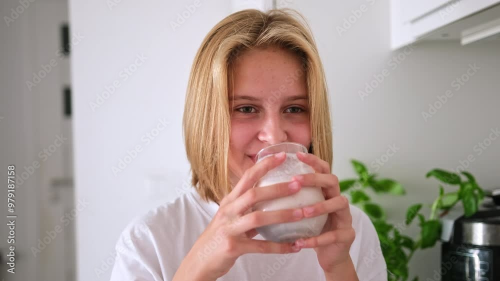 Cute Little Girl Drinking A Raspberry Milkshake From A Glass While Smiling In The Kitchen