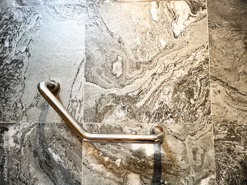 Stainless steel grab bar mounted on a marble bathroom wall, ideal for safety and accessibility in modern home design
