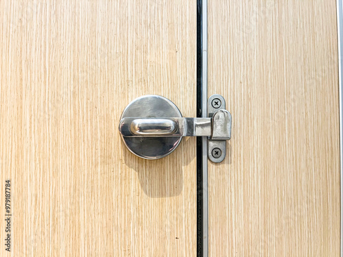 Minimalist stainless steel door latch on a wood-textured door, great for architecture, home improvement, and security topics photo