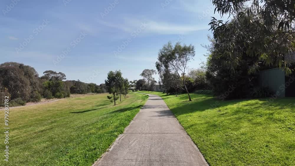 Walking backward, view from a concrete footpath in a large, open green space at Werribee River Trail, Melbourne. Beautiful outdoor environment in Victoria, Australia