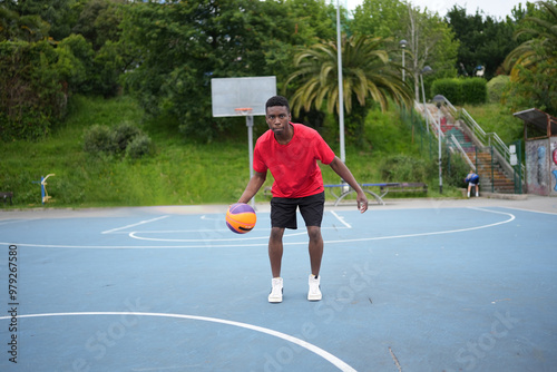 Afro man dribbling a basketball ball at the outdoor courtyard