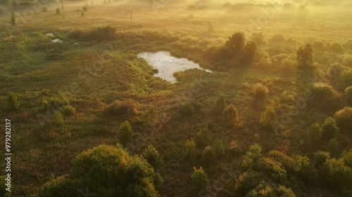 Aerial view of the meadows at dawn. The sun's rays break through the morning fog. Beautiful orange morning light, mist-shrouded forest, Cinematic aerial photography. High quality 4k footage