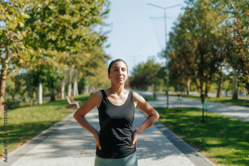 Fit young woman pausing after a workout session in the park on a bright sunny day. vertical shot Fit young woman pausing after a workout session in the park on a bright sunny day. vertical shot