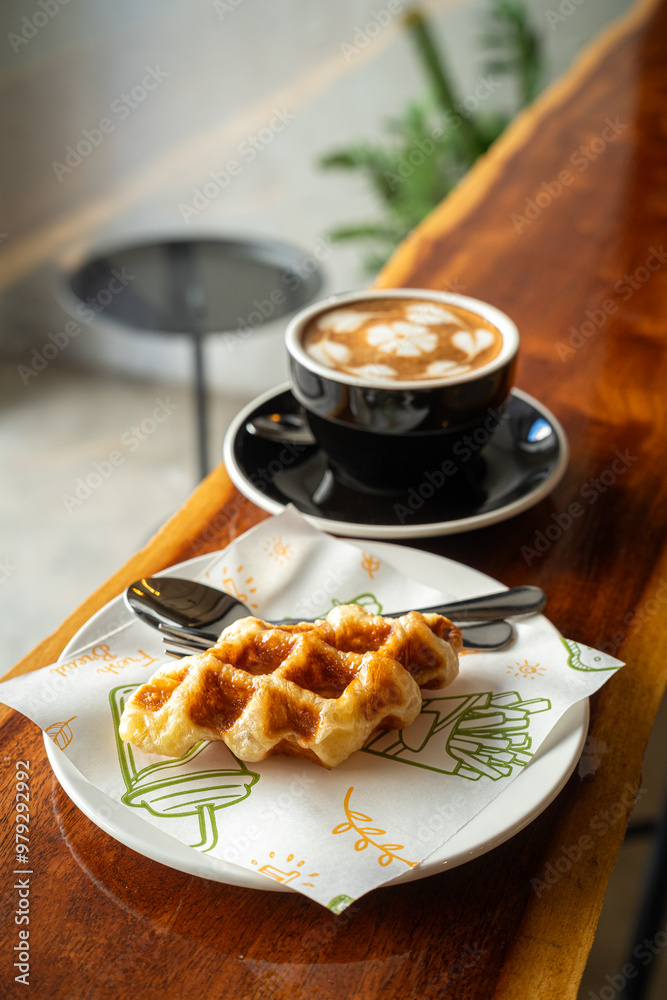 Hot coffee latte with latte art milk foam in cup mug and Homemade Belgian Waffles with honey on wood desk on top view. As breakfast In a coffee shop at the cafe,during business work.