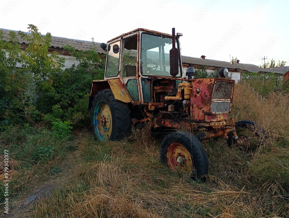Old rusty tractor in the yard under the open sky. Old non-working destroyed equipment. Agriculture and machinery for tillage. Old rusty tractor in the yard under the open sky. Old non-working destroyed equipment. Agriculture and machinery for tillage.