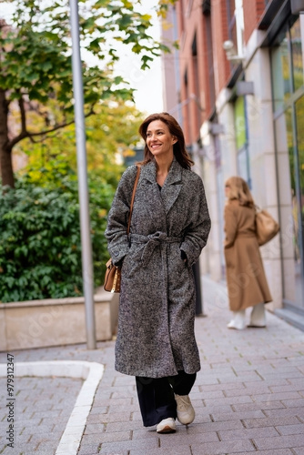 Attractive mid aged woman walking outdoors in city street on autumn day