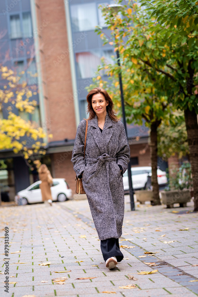 Fototapeta premium Attractive mid aged woman walking outdoors in city street on autumn day