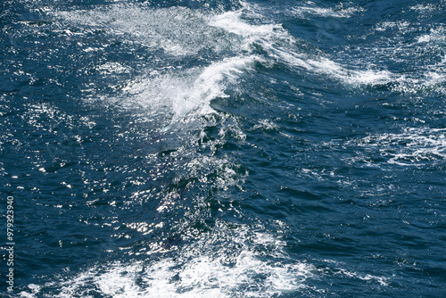 Blue water with ripples on the surface. Defocus blurred transparent blue colored clear calm water surface texture with splashes and bubbles. Water waves with shining pattern texture background.