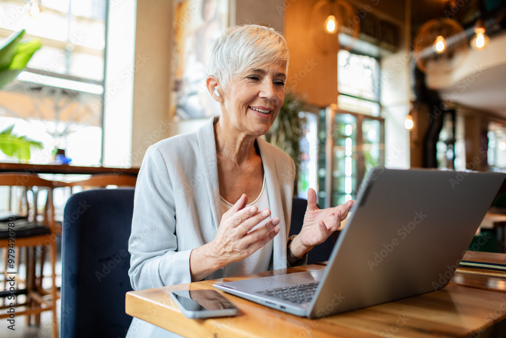 Senior businesswoman having video call on laptop in cafe Senior businesswoman having video call on laptop in cafe