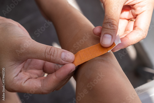 Bilde på lerret A mother is applying a band-aid to a scrape on her child's leg, who fell while p