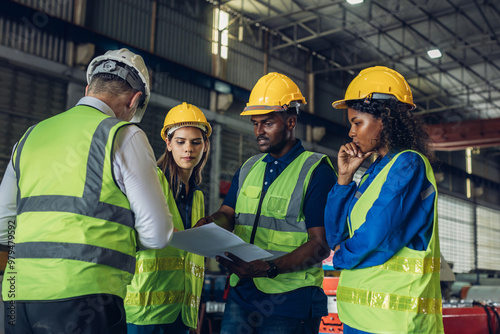 The Manager are taking a safety briefing before work. Implementation of safety culture at Factory. Factory Meeting: Chief Engineer Talking to Colleagues Before Work Day in Heavy Industry