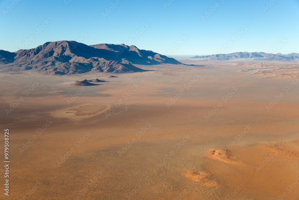 Aerial view of Arid desert plains and isolated mountain ridges at the edge of the Namib Desert. Namib Rand Nature Reserve, Namibia. Aerial view of Arid desert plains and isolated mountain ridges at the edge of the Namib Desert. Namib Rand Nature Reserve, Namibia.