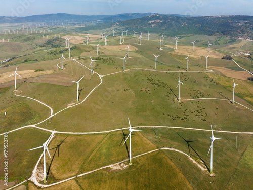 Aerial view of Windmills on a wind farm. In the background Zahara de los Atunes and the coastline of the Atlantic Ocean. Aerial view. Drone shot. Cádiz province, Andalusia, Spain. photo