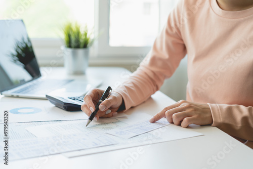 Deduction planning, debt asian young woman  hand using calculator to calculating money balance from bill and income, cost budget expenses for pay money form personal individual on table at home. photo