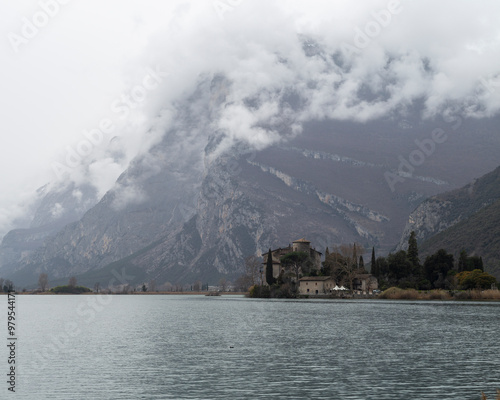 View of serene Toblino Lake with majestic Toblino Castle surrounded by mountains, Dolomites, Italy. photo