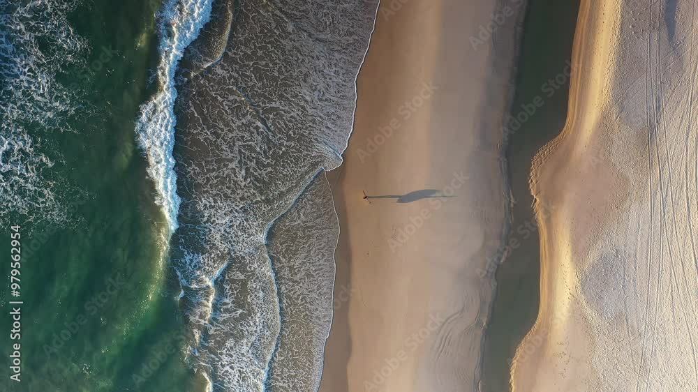 Aerial top down view of surfer walking into the ocean waves from Tallebudgera beach. Gold Coast