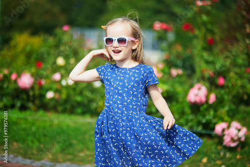 Adorable preschooler girl having fun in a green park on a summer day. #979576381