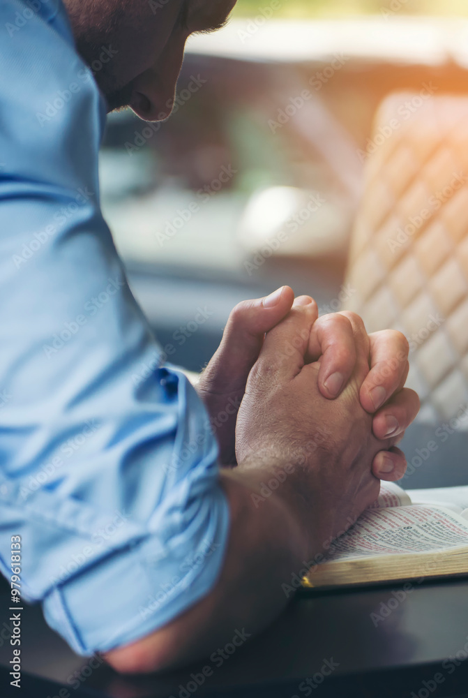 Obraz premium Pray and bible concept. Hand in hand together on bible by Caucasian man (worship christian), thinking and closed her eyes at church. Person side view, male praying, hope for peace-vertical image.