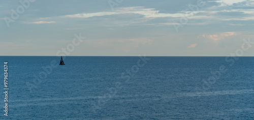 Sailboat with black sails sailing on calm sea under cloudy sky