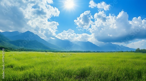 A serene landscape featuring mountains, lush green fields, and a bright blue sky with fluffy clouds.