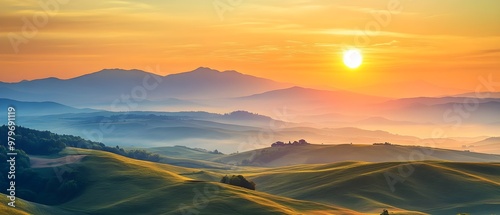 A beautiful sunrise illuminates rolling hills and distant mountains, casting soft light over a peaceful and misty landscape.