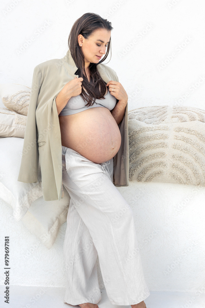 Stylish pregnant woman in a suit on a light background. Pregnancy concept. Stylish pregnant woman in a suit on a light background. Pregnancy concept.