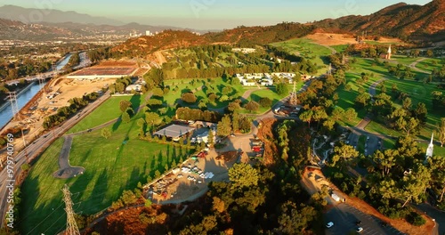 Rising over the beautiful green park located near the mount and a narrow rive. Cozy neighborhood of Los Angeles, California, United States.