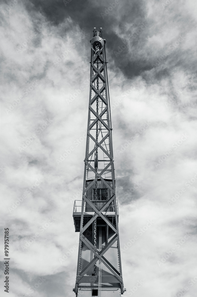 A vertical photo of the front of an old crane against a background of clouds. Black and white photo A vertical photo of the front of an old crane against a background of clouds. Black and white photo