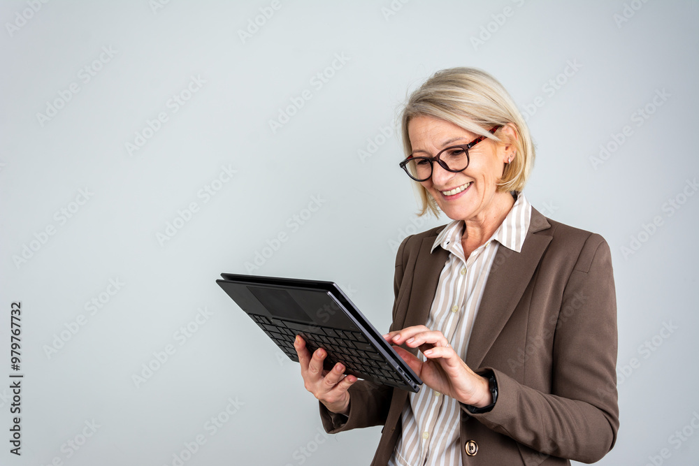 Portrait of happy mature businesswoman with touchpad isolated on grey background. Happy businesswoman using tablet over light grey background Portrait of happy mature businesswoman with touchpad isolated on grey background. Happy businesswoman using tablet over light grey background