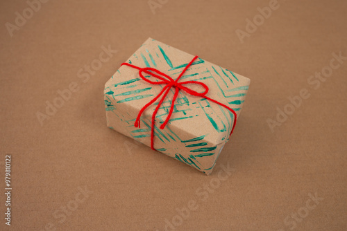 a gift wrapped in brown paper that has been decorated with green paint patterns created using the tines of a fork, crafting method personalized wrapping paper photo