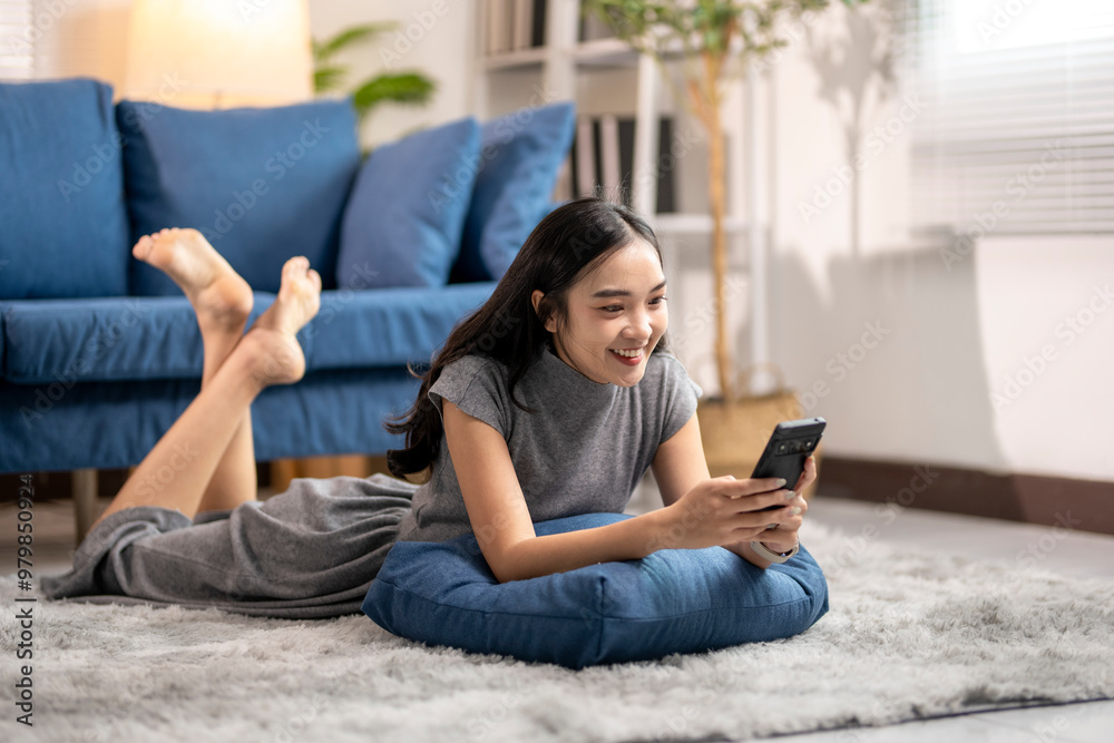 Happy young woman relaxing on floor at home using smartphone Happy young woman relaxing on floor at home using smartphone