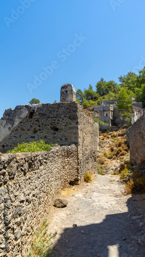 Road in abandoned town or village Kayakoy, neighbourhood of municipality and district of Fethiye, Mugla Province, Turkey. Vertical image photo