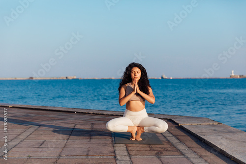 Athletic woman doing gymnastics yoga asana by the sea